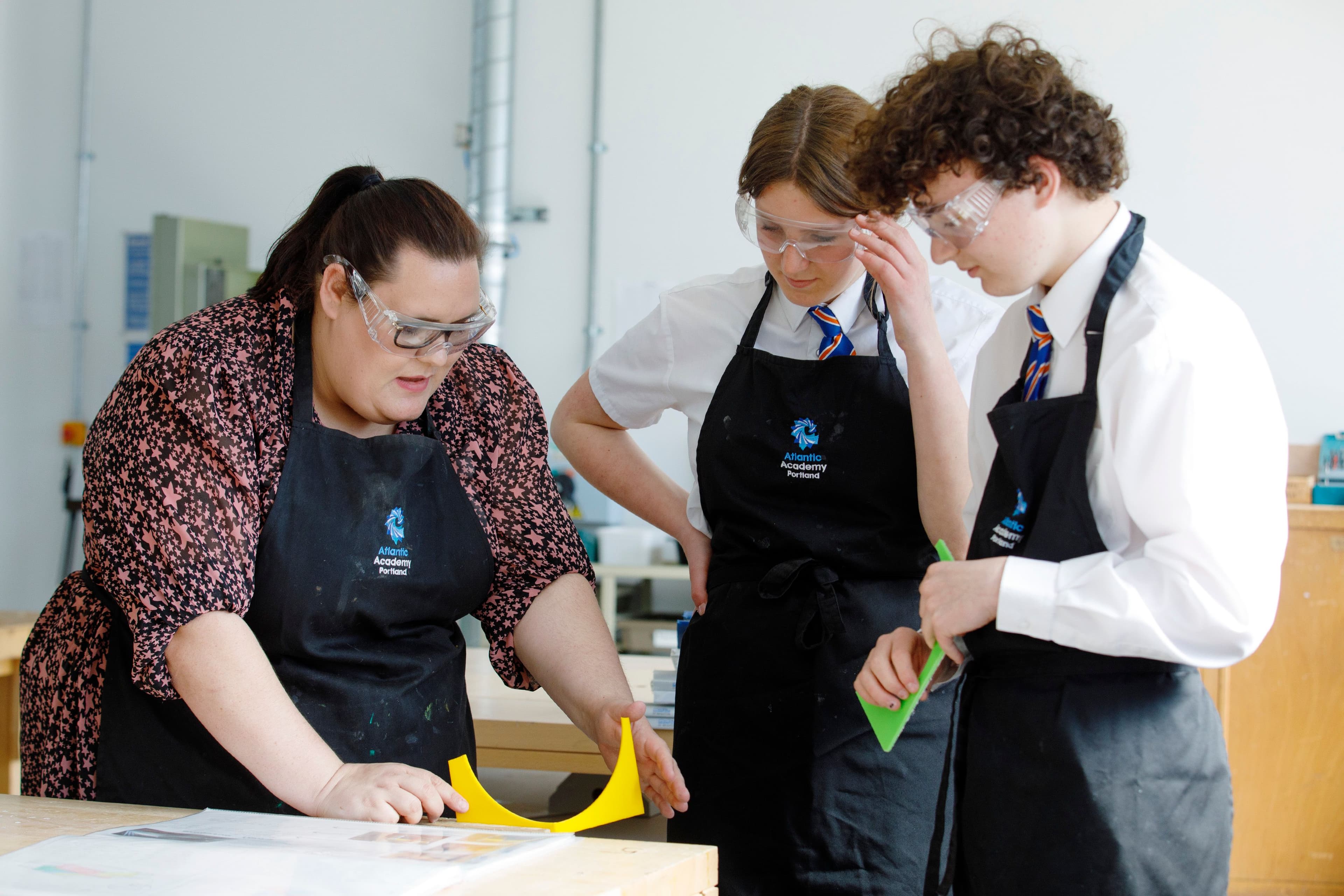 Two students work on a design and technology project with their teacher.