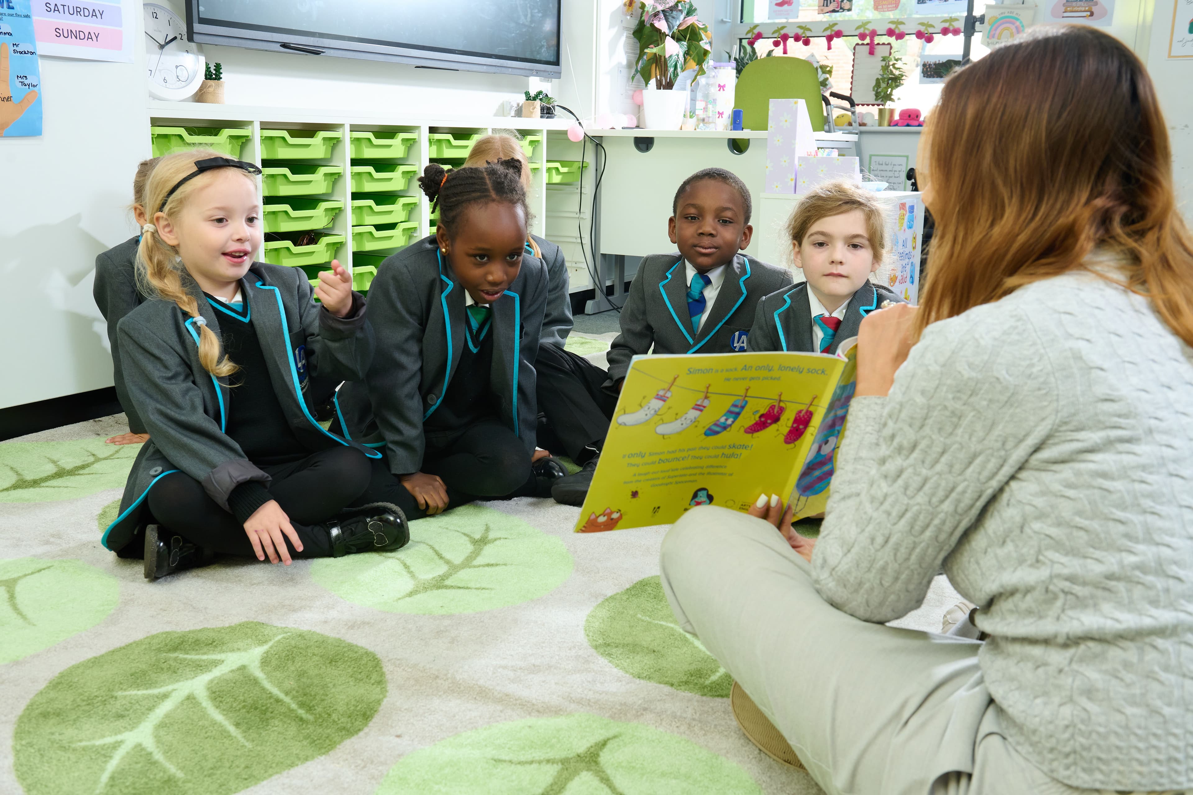 A group of young pupils reads a picture book with their teacher