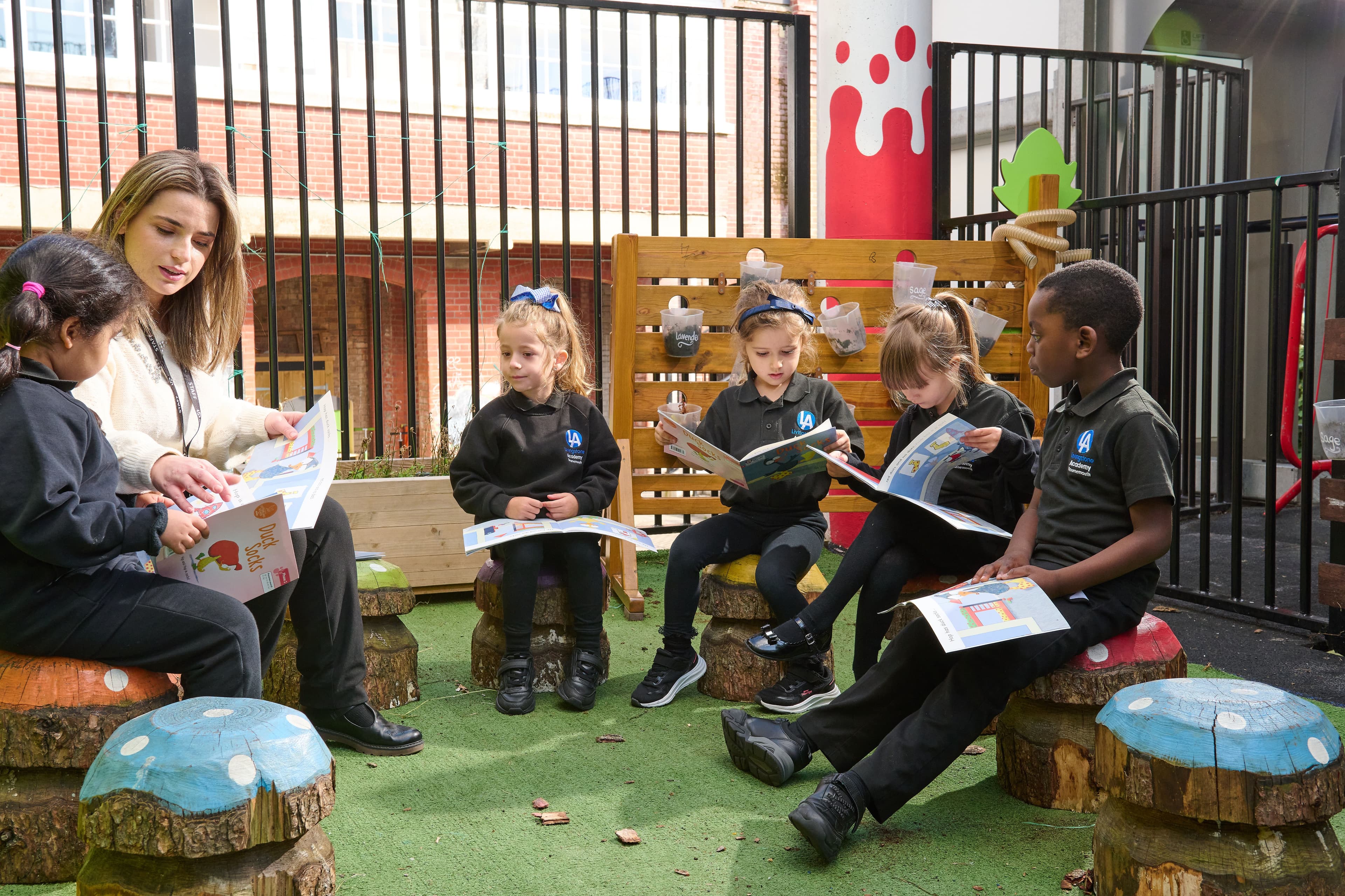 Teacher reads with a group of 5 students in a school garden