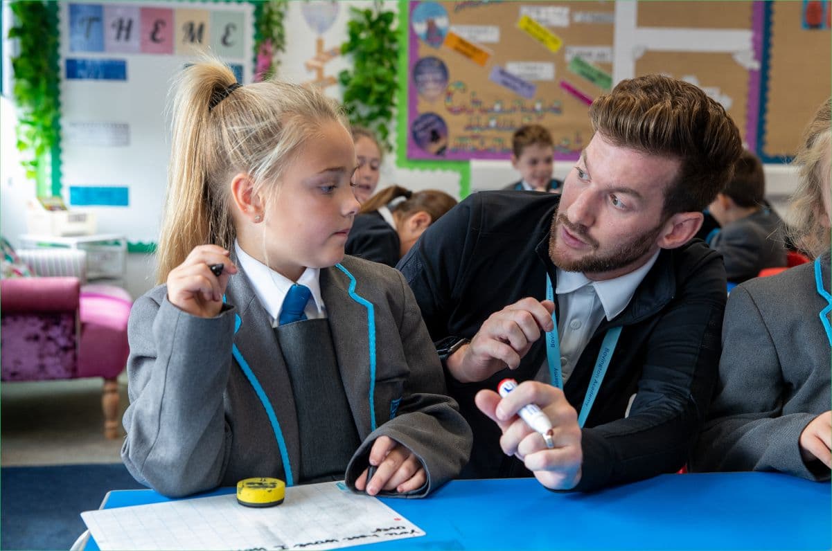 A teacher helps a student with their primary school work